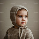 Toddler in cozy knitted bonnet looking away softly