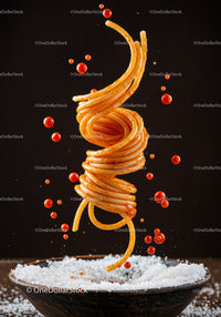 Floating spaghetti twirl with tomato sauce drops above bowl