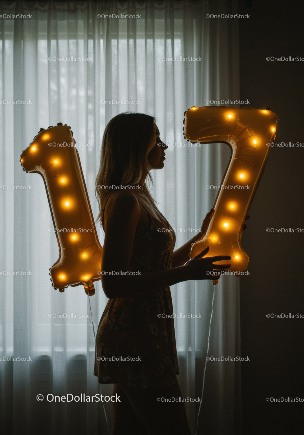 Sylwetka kobiety trzymającej podświetlane balony z 17 numerami