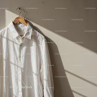 White Cotton Shirt Hanging on Wooden Hanger in Soft Light