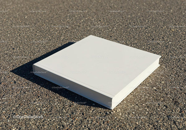 Closed white book lying on textured asphalt surface JPG Mockup Image