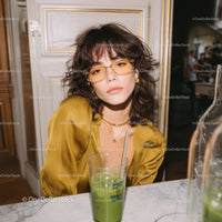 Stylish Woman with Curly Hair and Yellow Sunglasses Sitting at Cafe