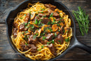 Beef Stew with Mushrooms and Pasta in a Rustic Skillet