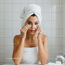 Young woman applying under eye patches in bathroom