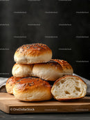Stacked freshly baked bread rolls with sesame seeds on wooden board