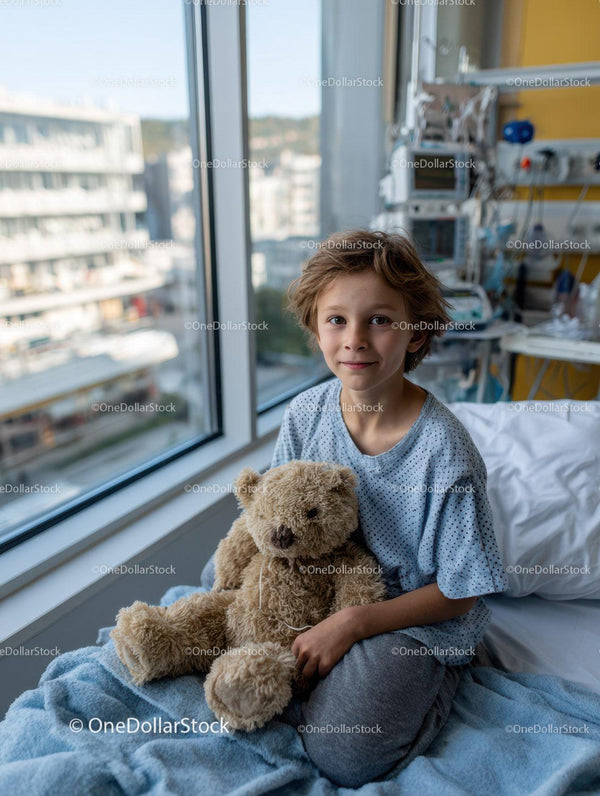 Young Boy Sitting on Hospital Bed with Teddy Bear Near Window