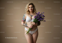Tattooed Woman Holding Violet Flowers in Lingerie Studio Portrait