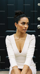 Elegant woman in white dress sitting by dark door