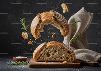 Rustic sourdough bread split with flying crumbs and herbs