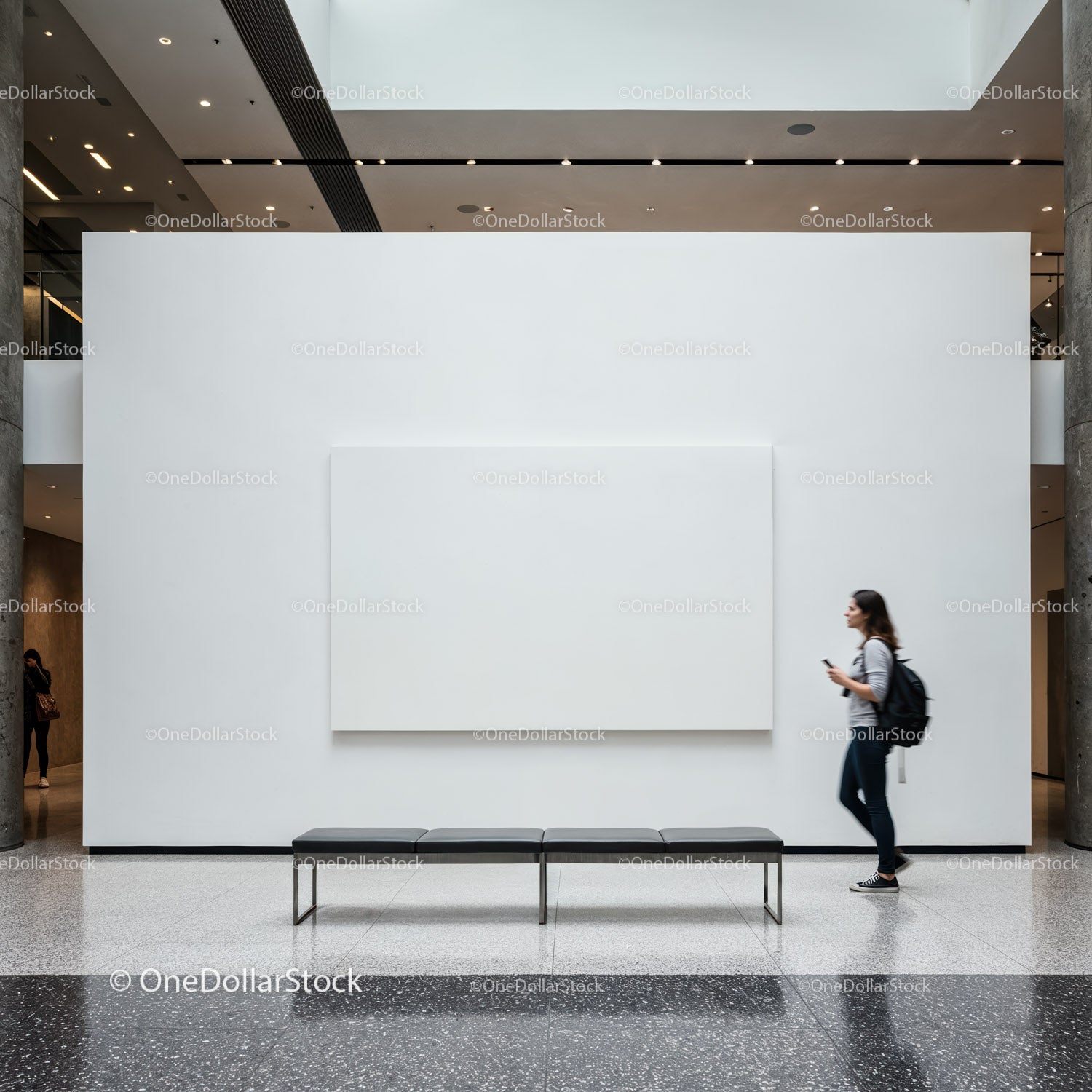 Young woman walking past white gallery wall with blank canvas