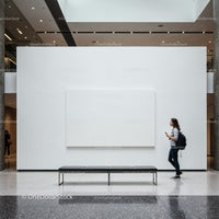 Young woman walking past white gallery wall with blank canvas