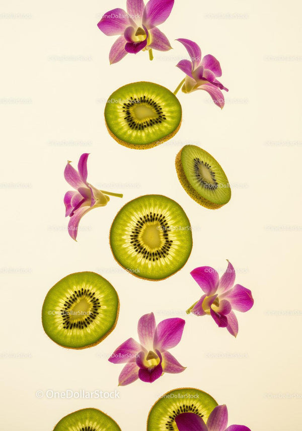 Kiwi slices with vibrant orchid flowers on light background