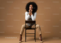 Thoughtful Woman Seated in Elegant Attire Against Brown Background