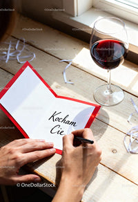 Handwriting a Romantic Note Near Glass of Red Wine