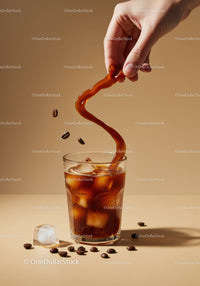 Hand Pouring Iced Coffee with Coffee Beans and Ice Cubes