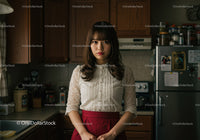 Young Woman Standing in Kitchen with Modern Appliances and Wooden Cabinets