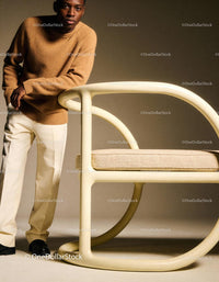 Young man leaning on modern beige chair in warm tones