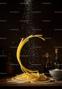 Raw Italian pasta with falling grated cheese on wooden table