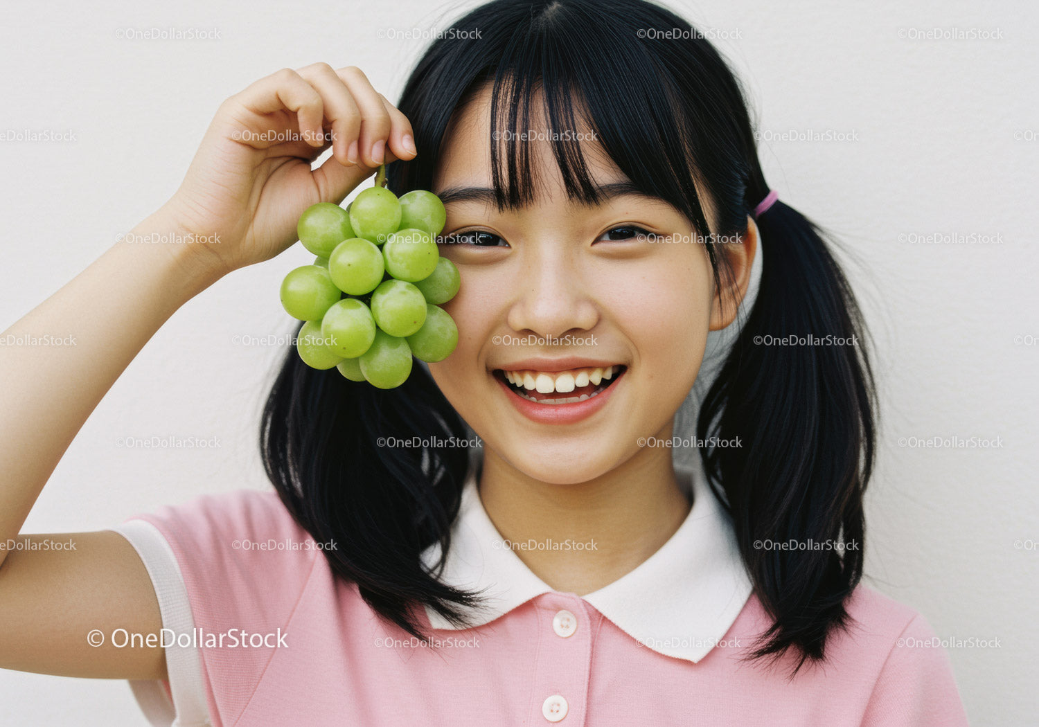 Happy Girl Holding Green Grape Cluster in Bright Indoor Setting
