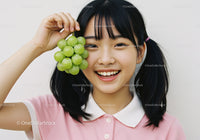 Happy Girl Holding Green Grape Cluster in Bright Indoor Setting