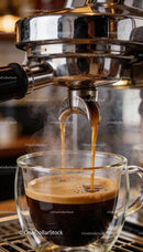 Freshly brewed espresso pouring into glass cup