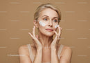 Woman Applying Face Cream with Skincare Products in Beige Background