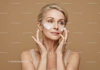 Woman Applying Face Cream with Skincare Products in Beige Background