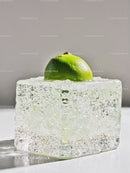 Fresh lime half resting on clear melting ice cube