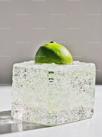 Fresh lime half resting on clear melting ice cube