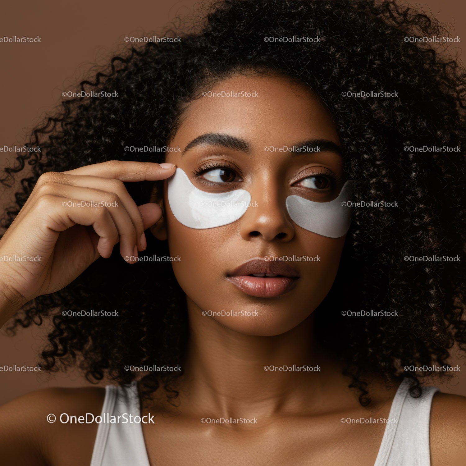 Woman with Curly Hair Applying Eye Patches for Skincare Therapy