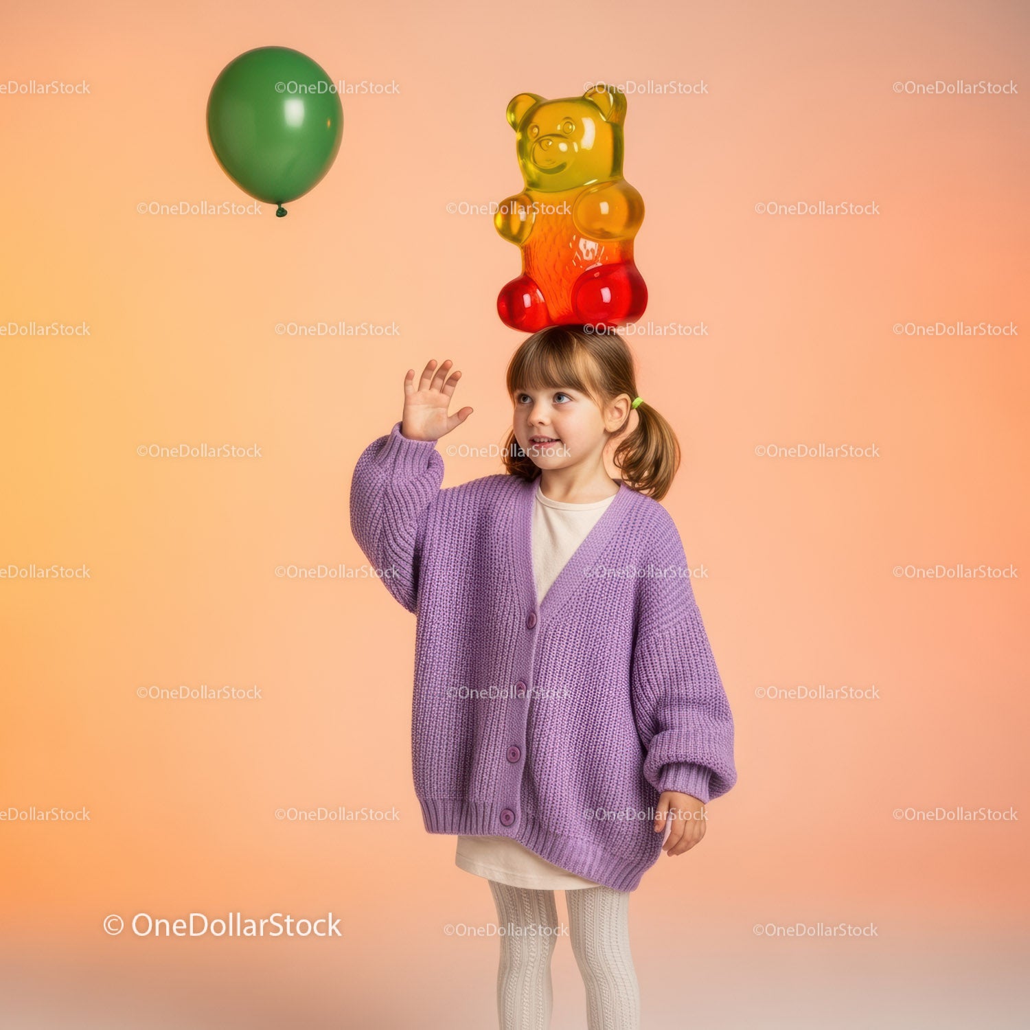 Little girl balancing giant gummy bear on head