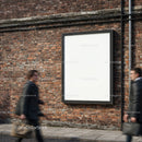 Blank advertising billboard on urban brick wall with busy pedestrians