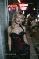 Stylish Young Woman Standing on City Street at Night with Neon Lights