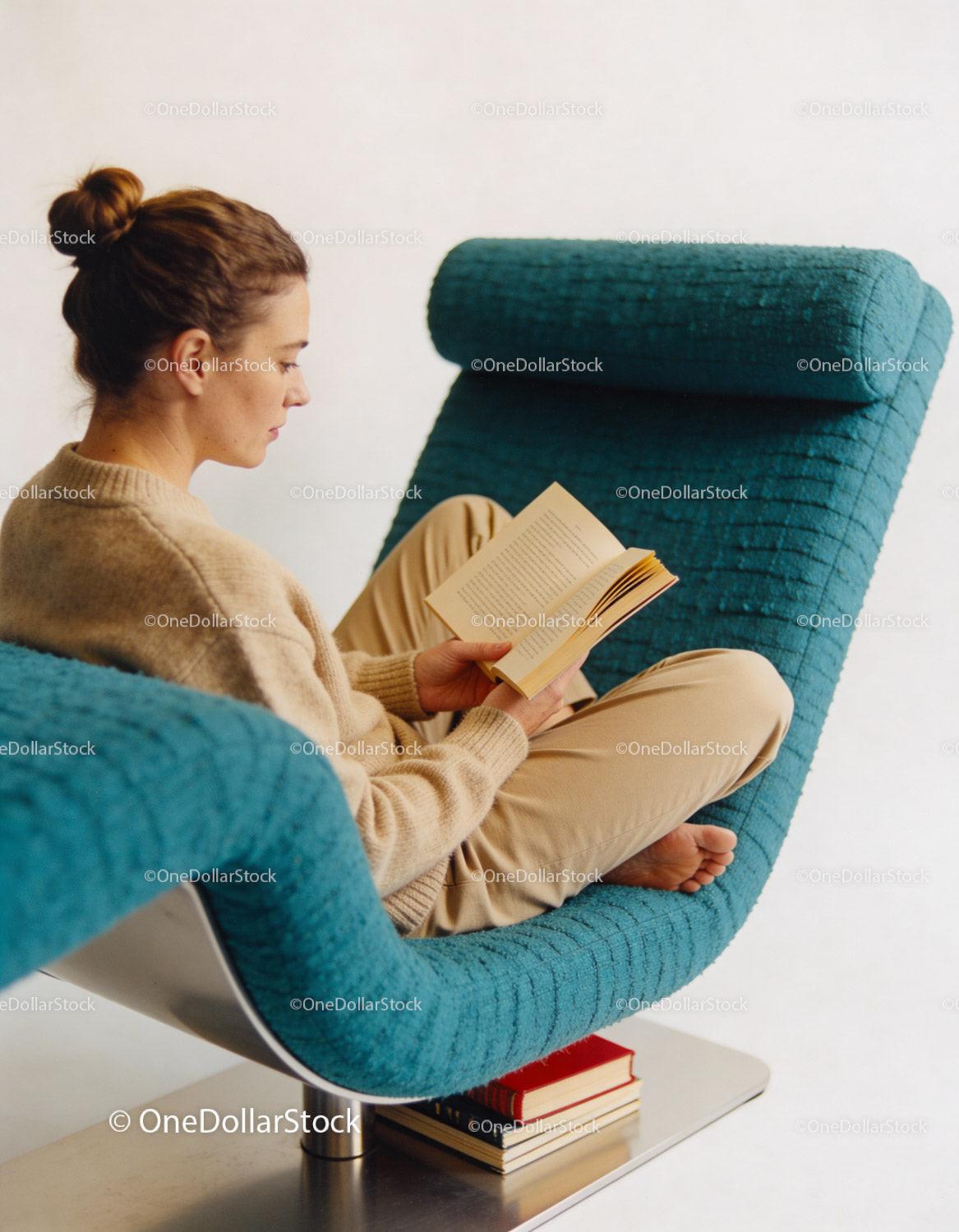 Woman Reading Book Relaxed in Modern Blue Chair