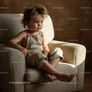 Thoughtful toddler sitting on cozy textured armchair