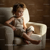 Thoughtful toddler sitting on cozy textured armchair
