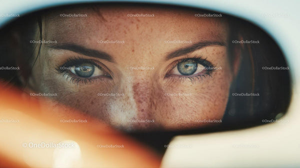 Close-up of Woman with Blue Eyes and Freckles Looking through Mirror