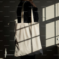Person holding plain natural cotton tote bag indoors