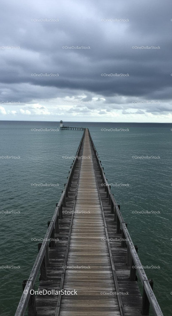 Wooden Pier Leading to Lighthouse Under Dramatic Cloudy Sky