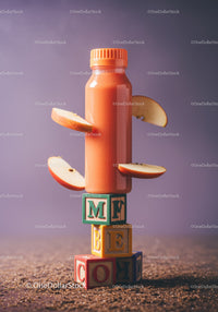 Orange smoothie bottle with apple slices on blocks