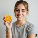 Bright Smiling Woman Holding Orange Half in Natural Light