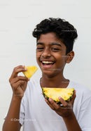 Joyful Child Enjoying Fresh Pineapple Slices Outdoor