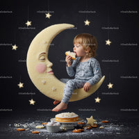 Toddler enjoying cake on crescent moon swing with stars