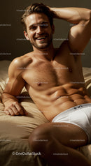 Smiling muscular man relaxing on bed in white underwear