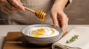 Close-Up of Honey Dripping from Wooden Dipstick into a Bowl