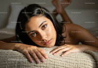 Young Woman Resting on Bed with Calm Expression in Cozy Bedroom