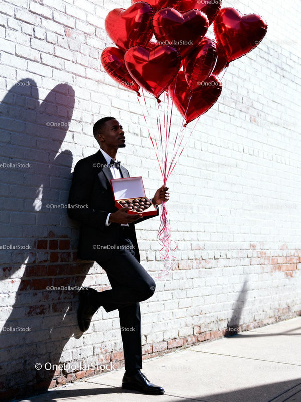 Man in Suit Holding Heart Balloons and Chocolates