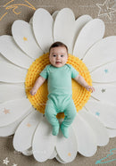 Smiling baby lying on giant daisy flower cushion