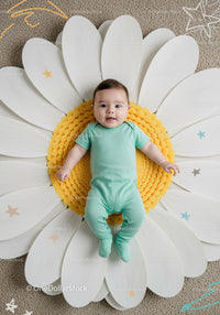 Smiling baby lying on giant daisy flower cushion