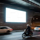 Motorcyclist and cars passing by illuminated billboard